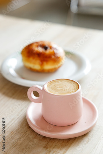 Cup of hot milk latte coffee on table by the window.