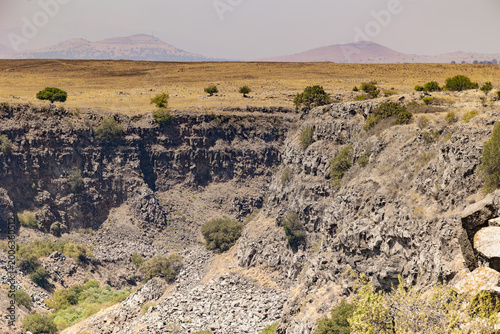 Εκτύπωση καμβά Horizontal wide angle eye level shot of a steep dark basalt cliff and rocky cany
