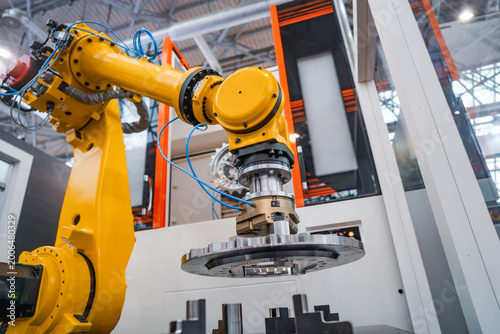 Industrial robotic arm holding metal gear component in automated factory cell.