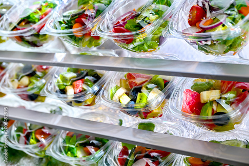 Plastic boxes with pre-packaged fruit and vegetable salads, put up for sale in a commercial refrigerator