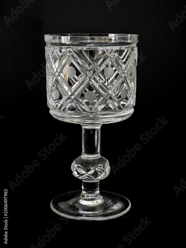 Vintage cut crystal goblet isolated on black background, decorative glassware with geometric pattern and elegant stem
