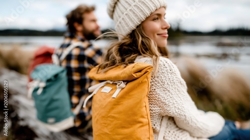 A joyful couple resting by a serene lakeside, showcasing their stylish backpacks while enjoying a moment of relaxation in the great outdoors surrounded by lush greenery.