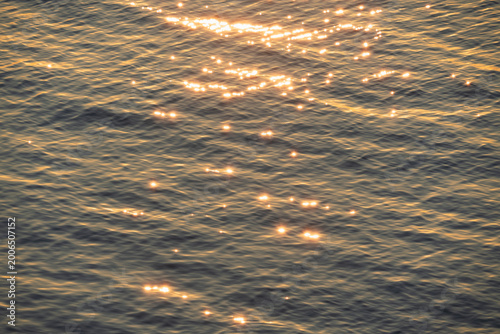 Beautiful golden sunlight reflecting on the rippling surface of the Baltic Sea during sunset, creating a shimmering water texture.