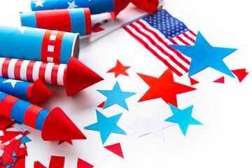 Fourth of July USA Independence Day festive celebration concept with copy space. Handmade craft paper rockets decorated with stars and stripes, USA flag, white background.