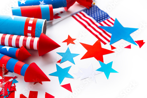 Fourth of July USA Independence Day festive celebration concept with copy space. Handmade craft paper rockets decorated with stars and stripes, USA flag, white background.
