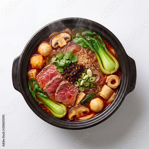 Spicy Malatang Beef Noodle Soup with Szechuan Chili Oil, Fresh Vegetables, and Meatballs in Black Ceramic Bowl on White Background