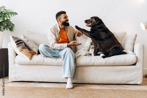 Man bonding with chocolate labrador dog on sofa
