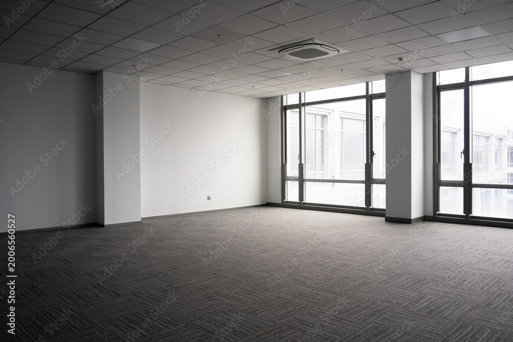 Naklejka premium Spacious empty office interior with gray carpet and large windows