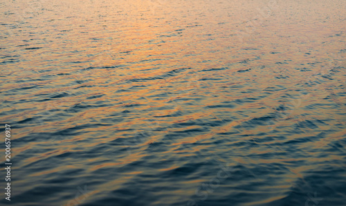 Purple and Blue Water Ripples Background at Sunset,Beautiful abstract texture of water surface with small ripples reflecting the purple and pink colors of the sunset sky, creating a serene and calm.