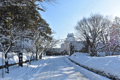 Snowy path leading to Aizu-Wakamatsu Castle under clear blue sky