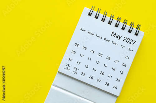 Top view of May 2027 calendar on yellow background with empty space for text.