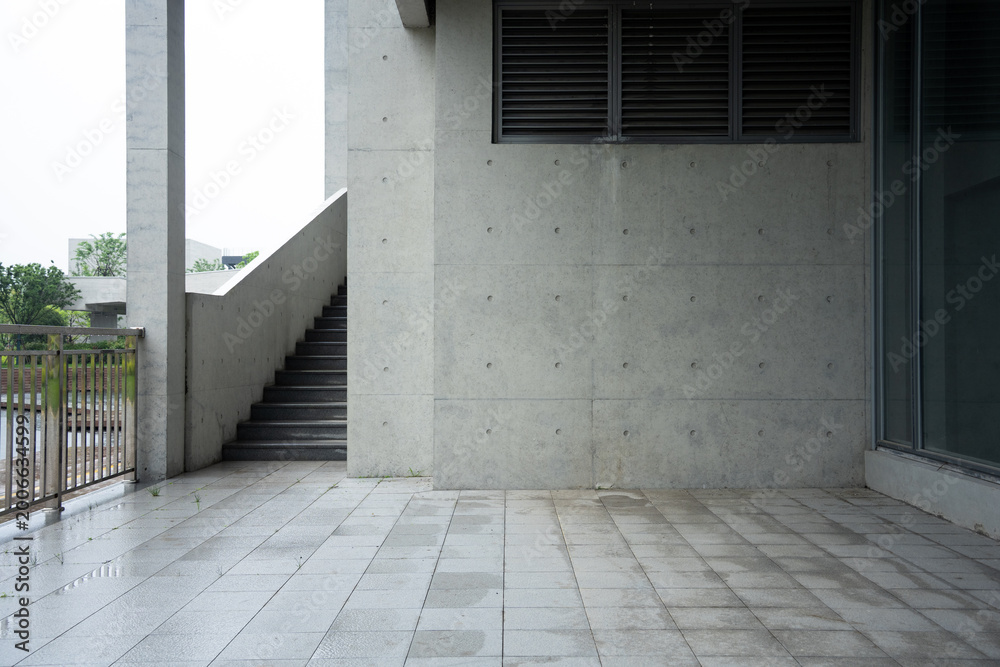 Fototapeta premium Concrete building exterior corridor with staircase and ventilation grille under overcast sky
