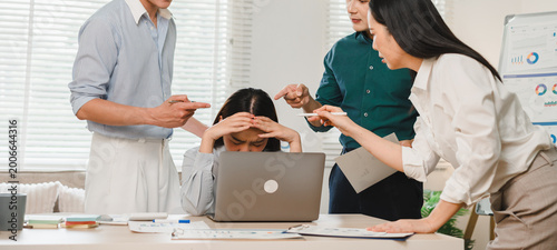 Stressed business woman feeling workplace bullying and professional harassment by coworkers in modern office environment