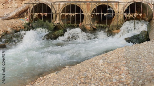 Slika na platnu Polluted water and wastewater discharge flows from several large concrete culverts, highlighting issues of urban runoff and environmental contamination