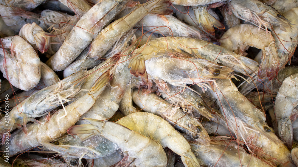 Fototapeta premium Close-up of a large heap of fresh uncooked prawns with shells and heads intact, displayed at a fish market
