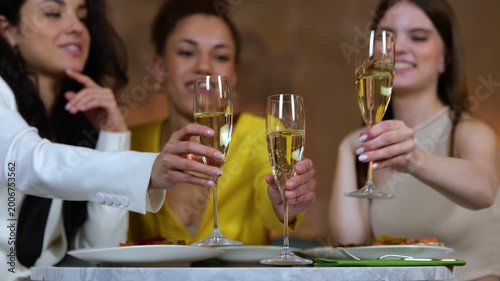 Happy young ladies having dinner in a restaurant and clinking glasses with champagne. Meeting of friends. Lifestyle, friendship concept. Real time video.