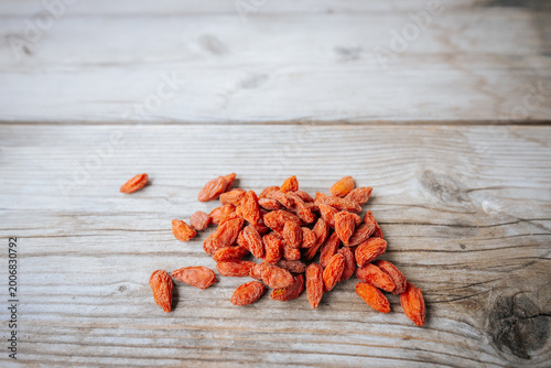 Foto Dried red goji berries scattered on a rustic wooden surface with shallow focus, highlighting the wrinkled texture and warm natural color