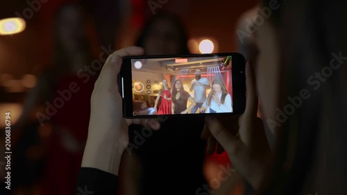 Female hands holding smartphone. Lady making video on the gadget. Friends dancing in the nightclub. Lifestyle, dance, disco concept. Real time.