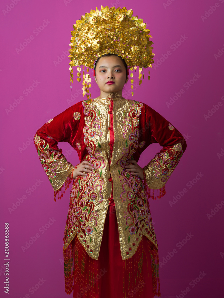 Obraz premium Young Indonesian Asian Woman In Traditional Red And Gold Chinese Wedding Costume With Ornate Golden Headdress