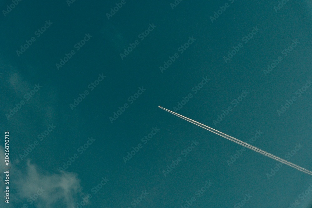 Fototapeta premium airplane with chemtrail in bright blue sky