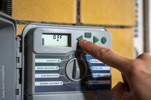 Cuadro en lienzo Finger pressing button on irrigation controller panel, adjusting automatic watering system settings with digital display and selector dial