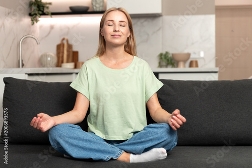 Free Download Woman sits on couch practicing mindfulness and meditation at home - GFXLoad