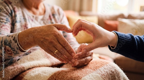 Caregiver and senior woman forming heart shape with hands