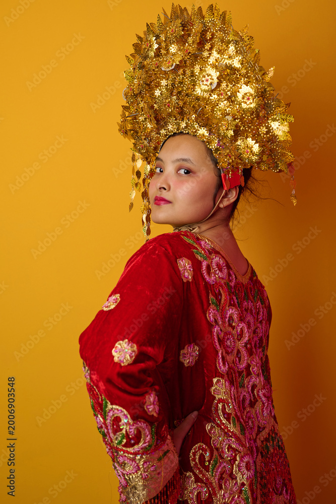 Fototapeta premium Young Indonesian Asian Woman Wearing Golden Headdress And Embroidered Red Traditional Costume Portrait