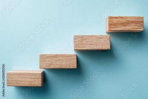 Wooden Blocks Arranged in a Staircase on a Blue Background.
