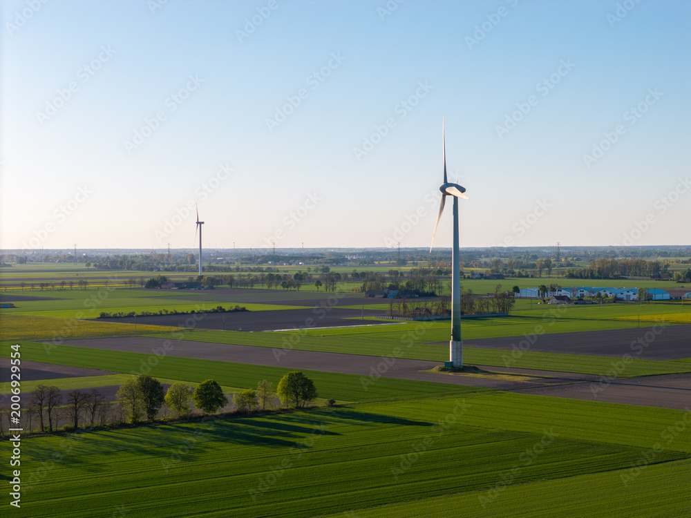 Fototapeta premium Wind Farm Fields: Renewable Energy Landscape in Vast Green Farmland