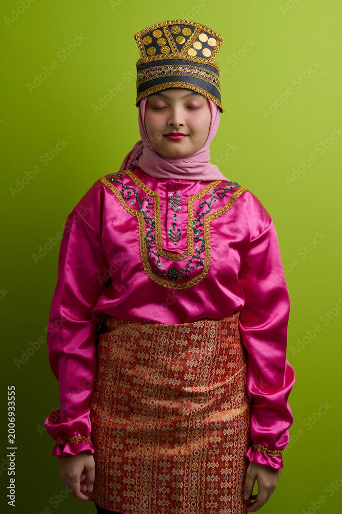 Fototapeta premium Young Indonesian Asian Woman in Traditional Malay Costume and Hijab Wearing Ornate Headdress and Songket Skirt