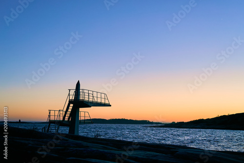 Silhouette of a Diving Board at a Coastal Nordic Beach During a Vibrant Summer Sunset