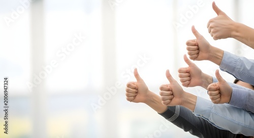 Group of business people showing thumbs up gesture of approval and success in a bright office background with copy space