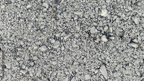 Vászonkép A high-angle, close-up shot of fresh grey asphalt, showing a dense, textured mixture of small crushed stones, angular mineral aggregates, and fine bitumen binder particles