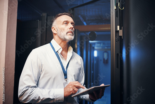 Tablet, man and rack inspection in server room for cybersecurity, hardware maintenance or solution. IT technician, mature person or tech in data center for system backup, troubleshoot or diagnostics