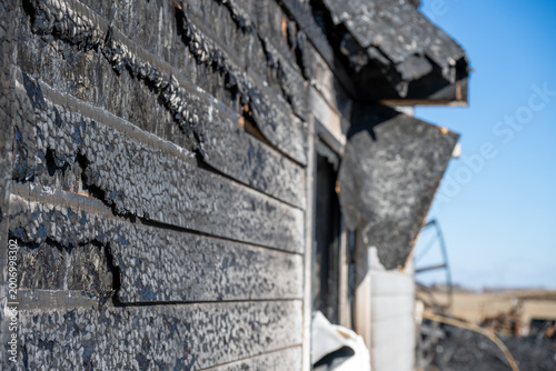 Charred exterior of a building after a fire in an open landscape on a clear day