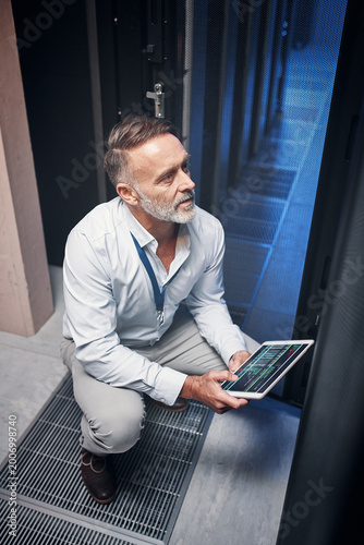 Tablet, man and technician with inspection, update or engineer on app in data center. Cybersecurity, database and mature programmer in server room with network maintenance or code for software