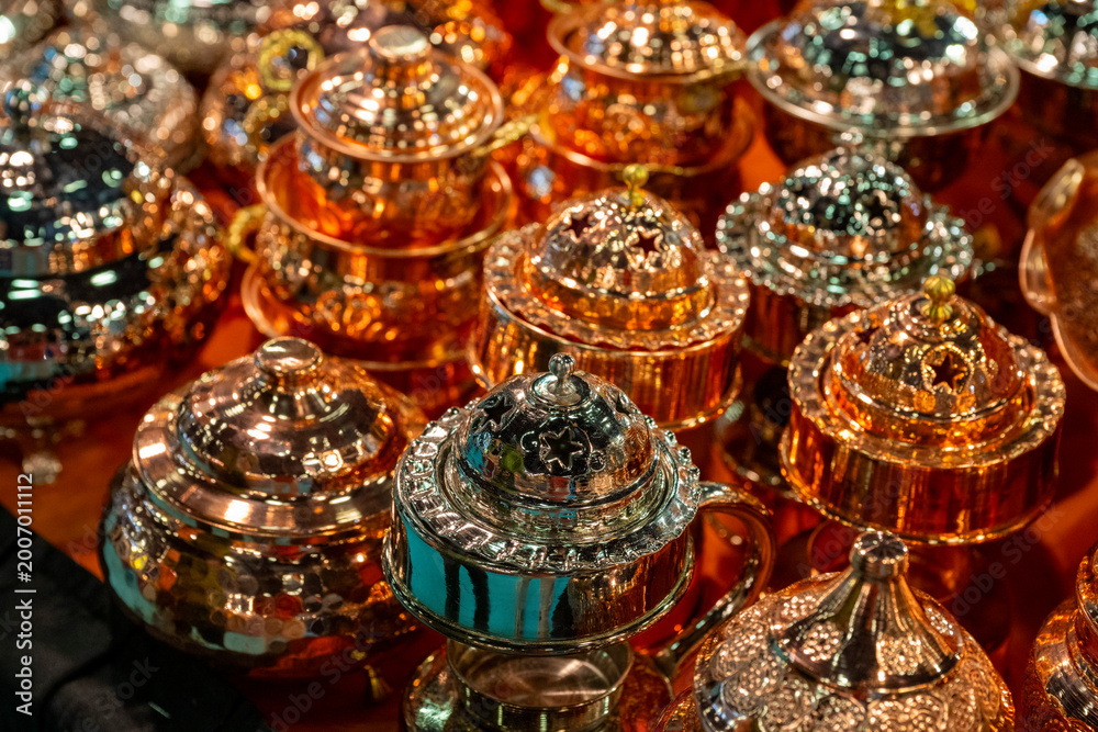 Fototapeta premium Metal coffee cezve with decorative oriental pattern on the shop window. Household items copper items for sale. Cupric coffeepots at the bazaar in Antalya Turkey. Turkish coffee pots. Metal coffee cezv