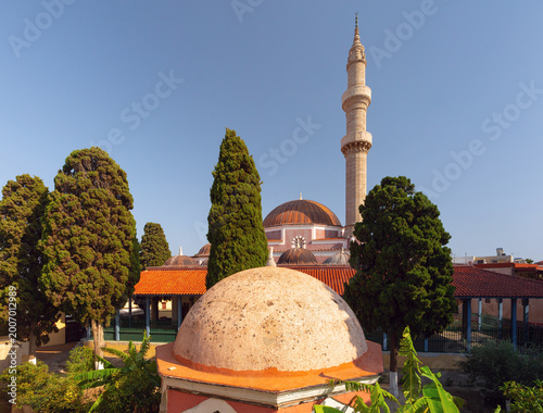 Mosque with minaret and domes among trees in old town of Rhodes Greece