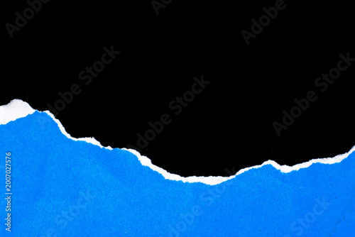 Fotografi Torn paper reveals a stark black void against vivid blue