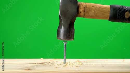 Hammer striking nail on wooden plank, close-up, green screen background