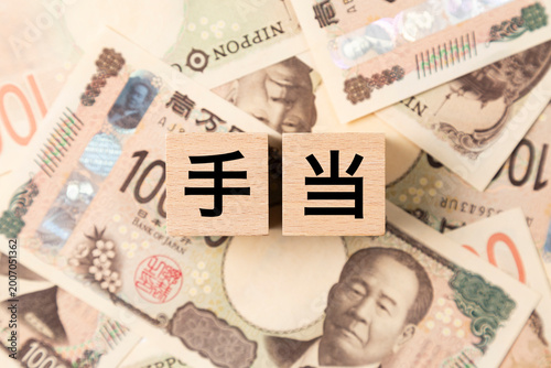 「手当」と書かれたブロックとたくさんの一万円札
