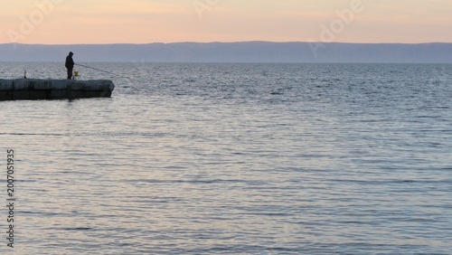 Cuadro en lienzo A man with a fishing rod fishes on a pier on Lake Baikal