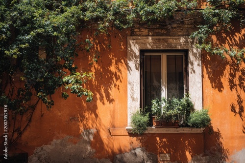 Charming Window Adorned with Lush Greenery on an Orange Textured Wall.