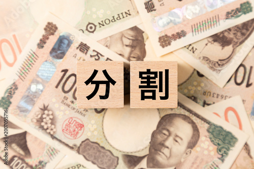 「分割」と書かれたブロックとたくさんの一万円札