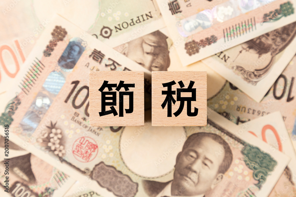 Fototapeta premium 「節税」と書かれたブロックとたくさんの一万円札