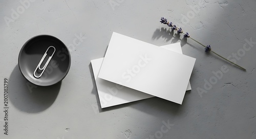 Blank white business cards with silver paperclip in black bowl and sprig of lavender on concrete