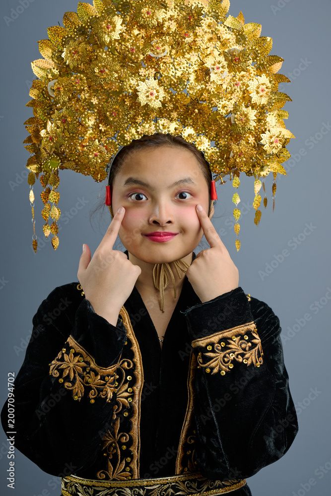 Fototapeta premium Young Indonesian Asian Girl Wearing Ornate Gold Traditional Headdress and Embroidered Costume Portrait