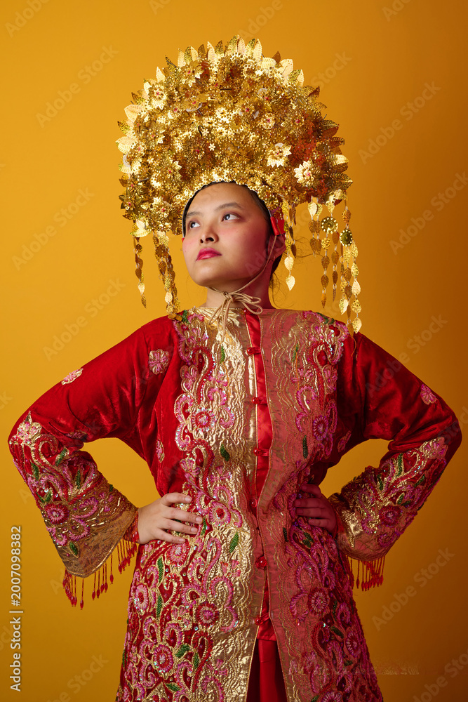 Fototapeta premium Young Indonesian Asian Woman Wearing Ornate Gold Headdress and Red Traditional Costume Portrait for Cultural Celebration