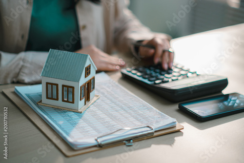Real estate and financial planning house model on documents, calculator and smartphone, mortgage calculation, property investment, home loan, budgeting, and personal finance management